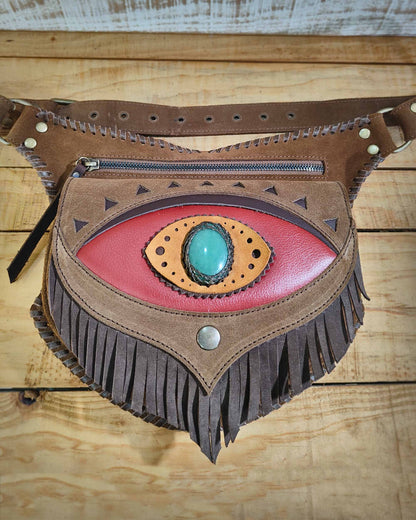 Handcrafted leather belt bag by Bohonito featuring a red flap with fringes, third eye Ajna detail, and artisanal hand-lacing.