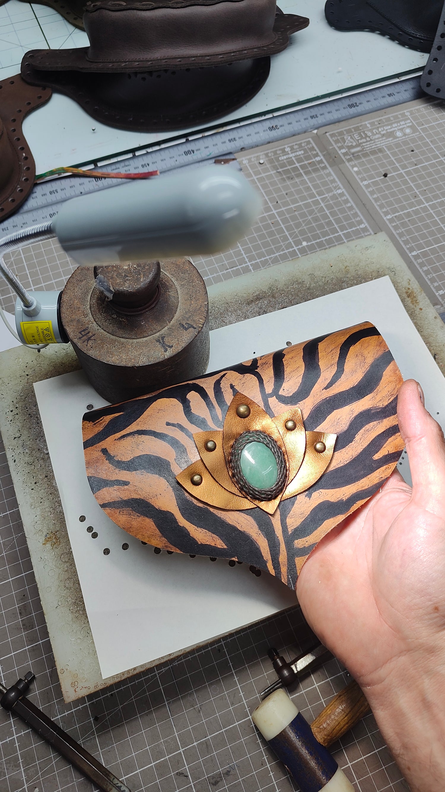 Bohonito handcrafted leather flap featuring a tiger-print pattern, a metallic lotus flower appliqué, and a natural green aventurine stone.
