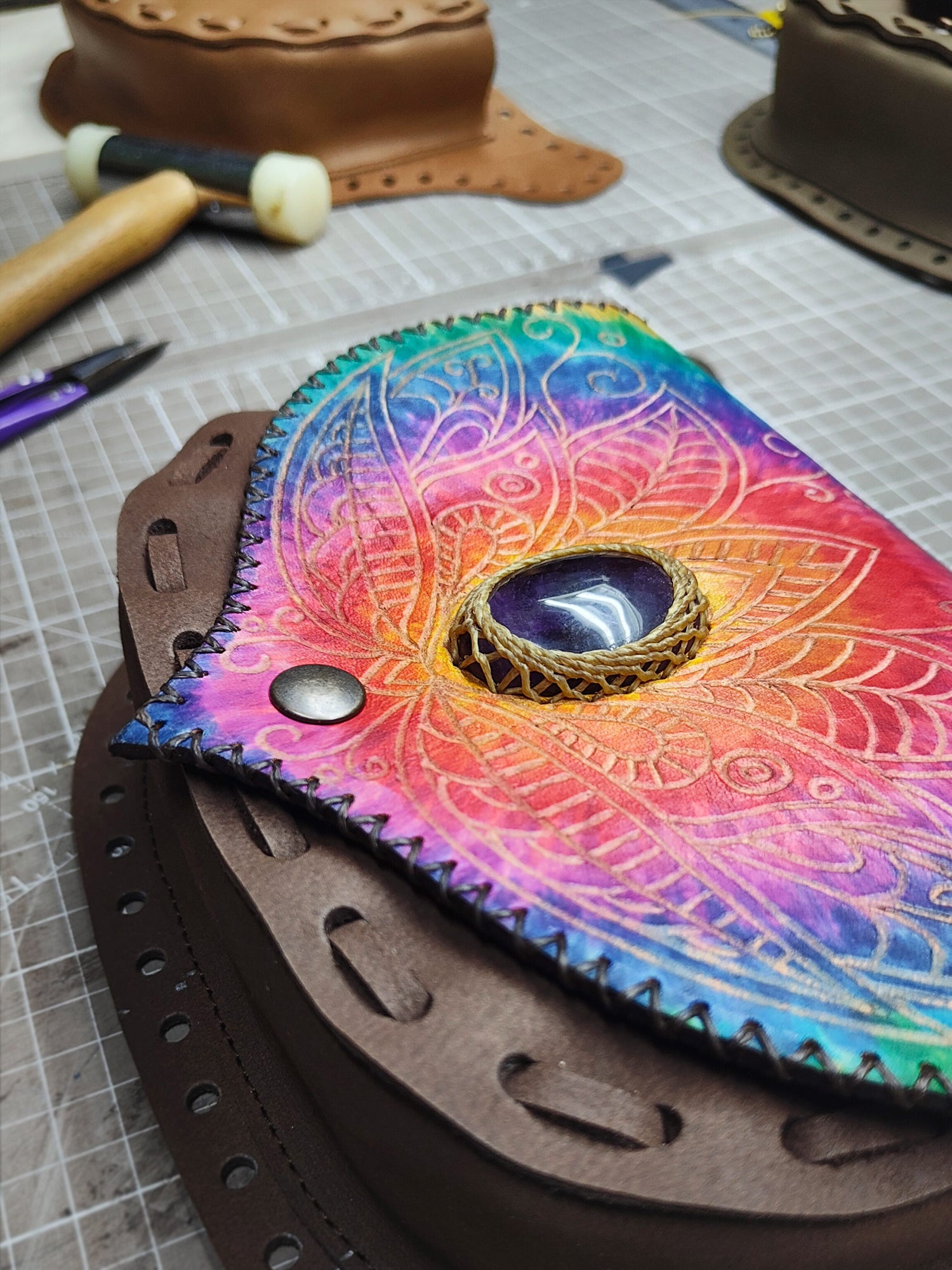 Handcrafted leather belt bag by Bohonito featuring a vibrant tie-dye leather flap with hand-pyrographed an amethyst gemstone with macrame stone setting